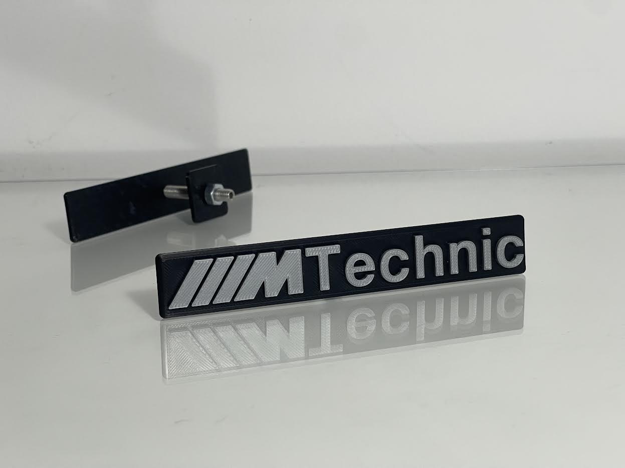 BMW ///M Technic Emblem rear view showing adhesive backing or clip-on mounting