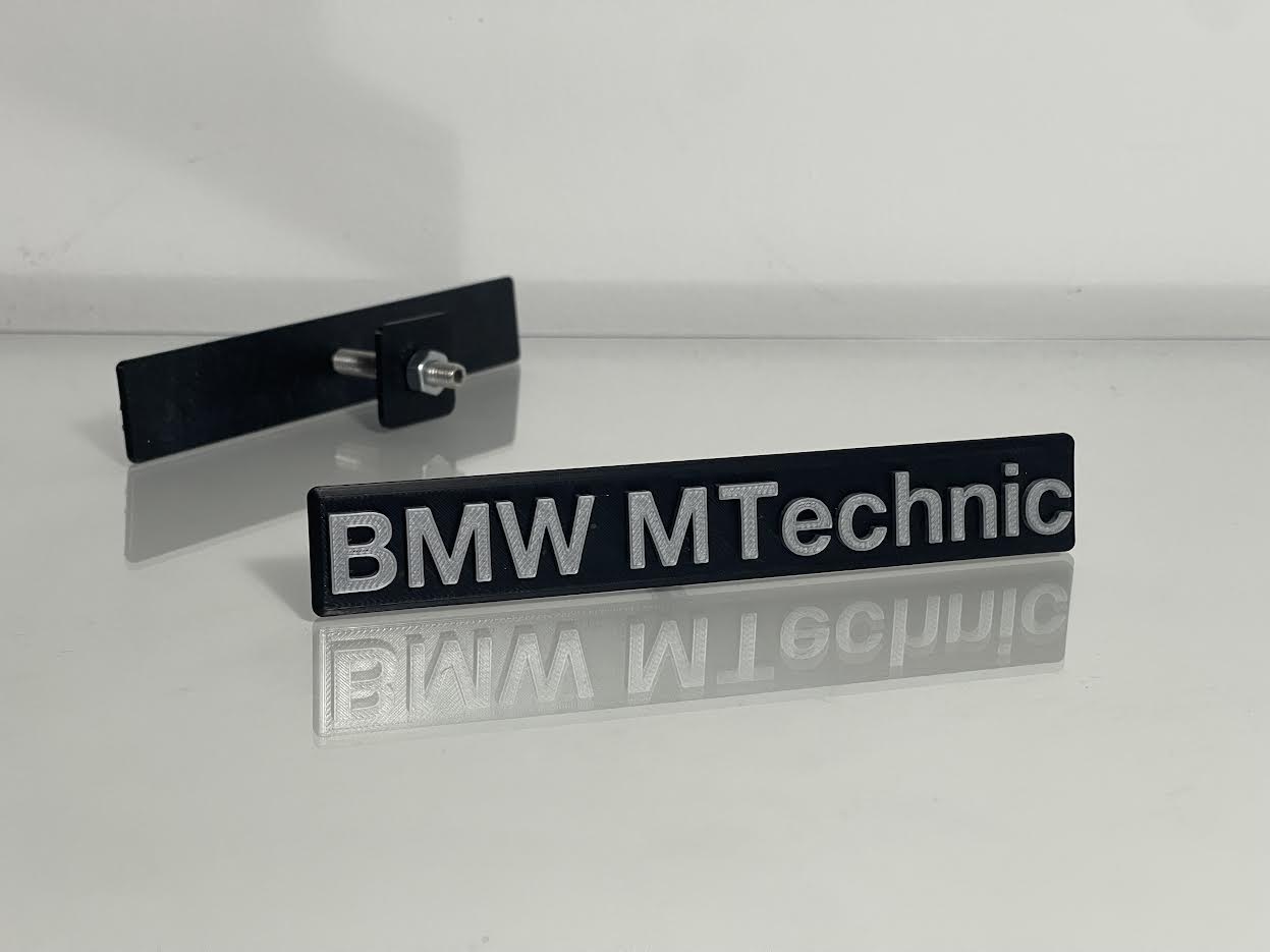 BMW M Technic Emblem rear view showing adhesive backing or clip-on mounting system