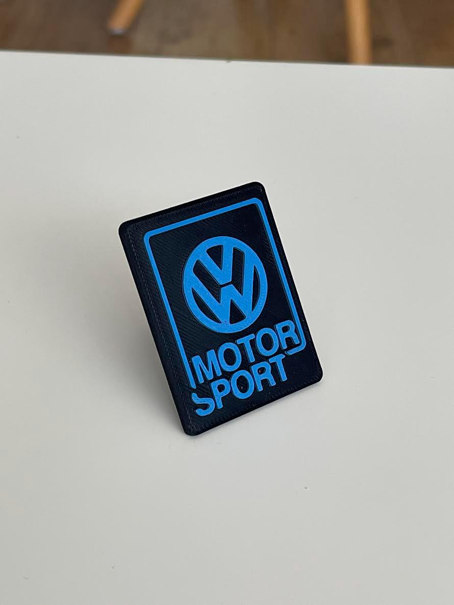 Blue Volkswagen Motorsport emblem with black lettering, 3D printed for universal Volkswagen front grille installation.