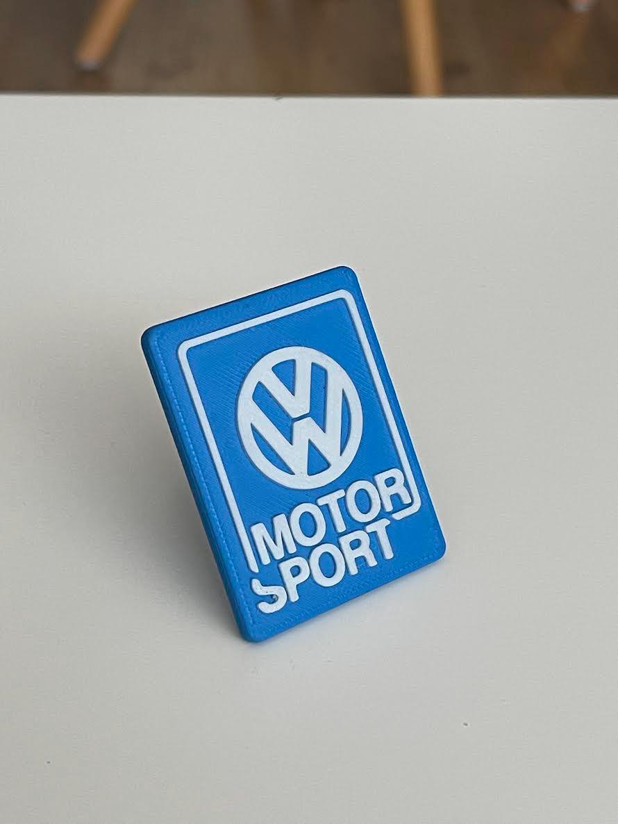 White Volkswagen Motorsport emblem with a blue background, 3D printed for universal Volkswagen front grille installation.